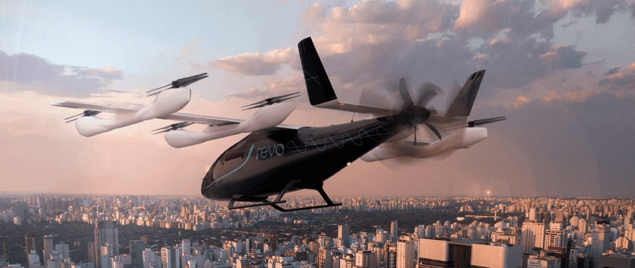 An Eve Air Mobility Revo electric vertical takeoff and landing vehicle in the sky. An Eve Air Mobility Revo electric vertical takeoff and landing vehicle in the sky.