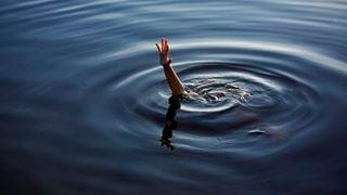 A drowning hand reaching out of a body of water A drowning hand reaching out of a body of water
