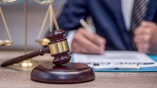 A man in a suit sitting with a gavel A man in a suit sitting with a gavel