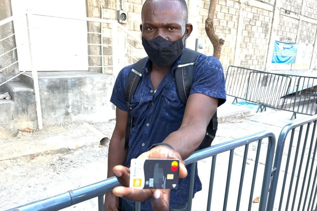 A migrant holding up a debit card given to him by the United Nations. A migrant holding up a debit card given to him by the United Nations.