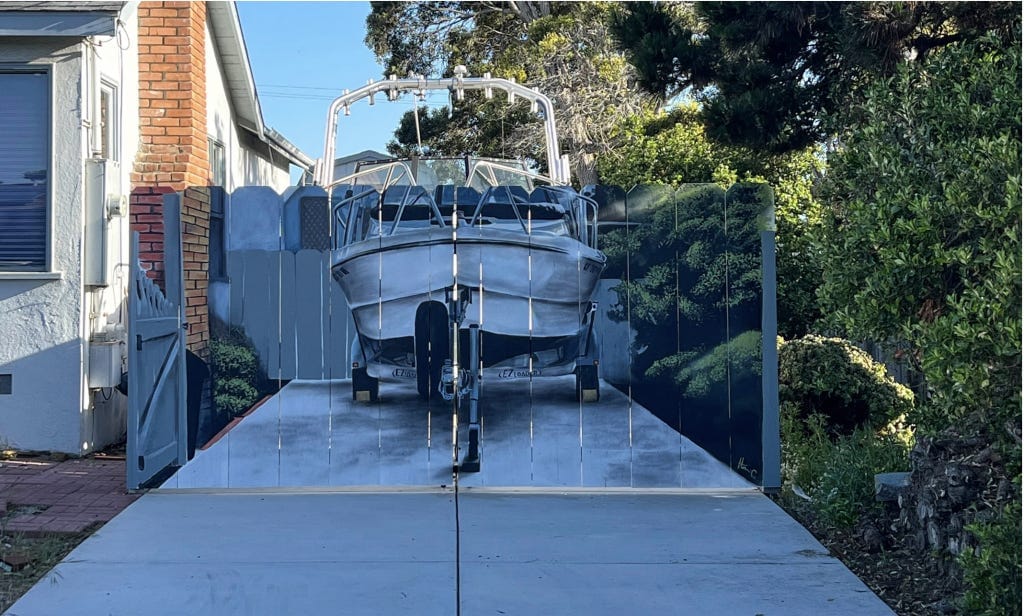 A fence hiding a boat in a driveway has a boat painted on it by artist Hanif Panni A fence hiding a boat in a driveway has a boat painted on it by artist Hanif Panni