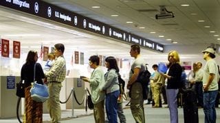 A line of people at an immigration office A line of people at an immigration office