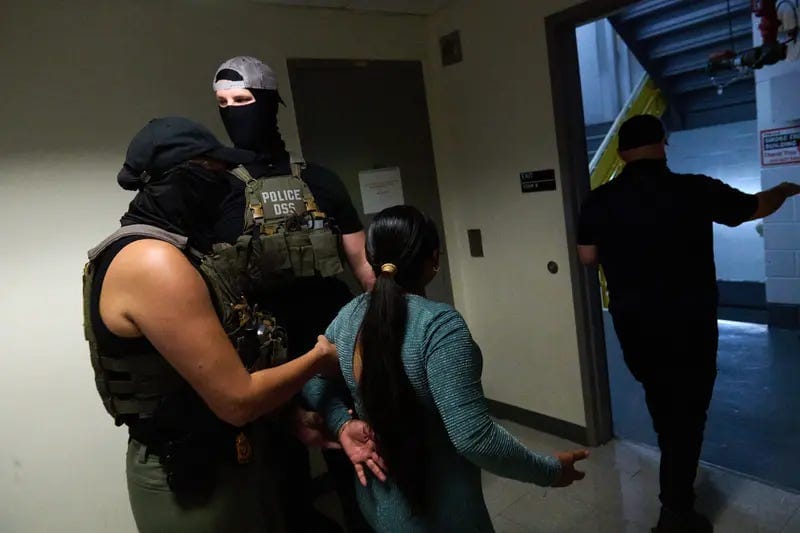 First image: People wait in line while an agent in a black mask and hat leans against a wall. Second image: Masked agents restrain the arms of a man wearing glasses and a blue shirt. Third image: Two masked agents wearing hats detain a woman, seen from behind. First image: People wait in line while an agent in a black mask and hat leans against a wall. Second image: Masked agents restrain the arms of a man wearing glasses and a blue shirt. Third image: Two masked agents wearing hats detain a woman, seen from behind.