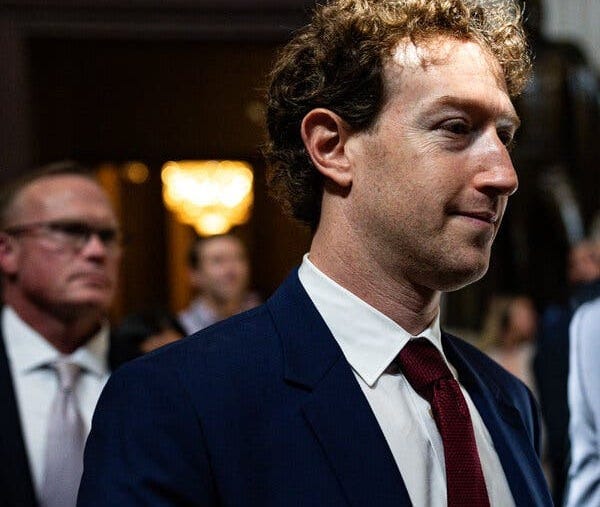 Mark Zuckerberg, wearing a dark blue suit, white shirt, and red tie. Mark Zuckerberg, wearing a dark blue suit, white shirt, and red tie.
