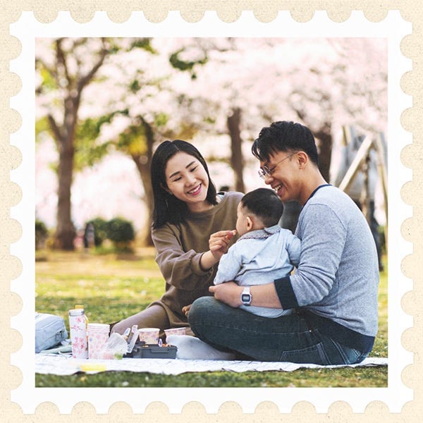 Image of a Japanese family sitting on a blanket with a baby under a blossoming cherry tree Image of a Japanese family sitting on a blanket with a baby under a blossoming cherry tree