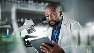 A man sitting at a microscope A man sitting at a microscope