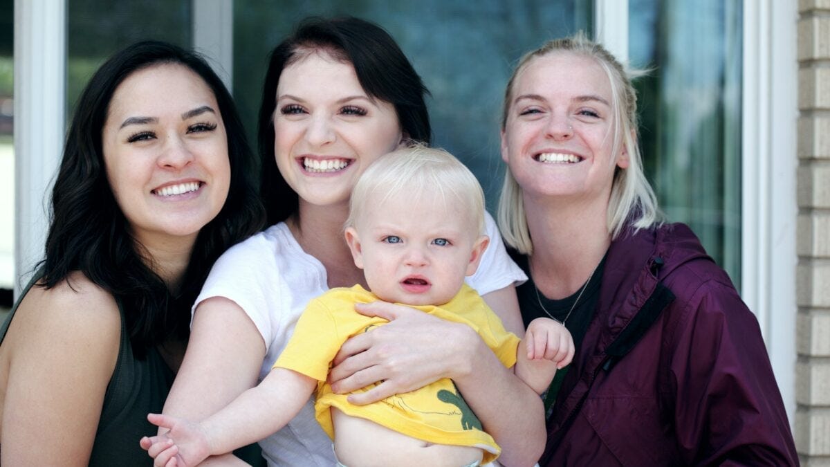 three young women with one young baby boy three young women with one young baby boy