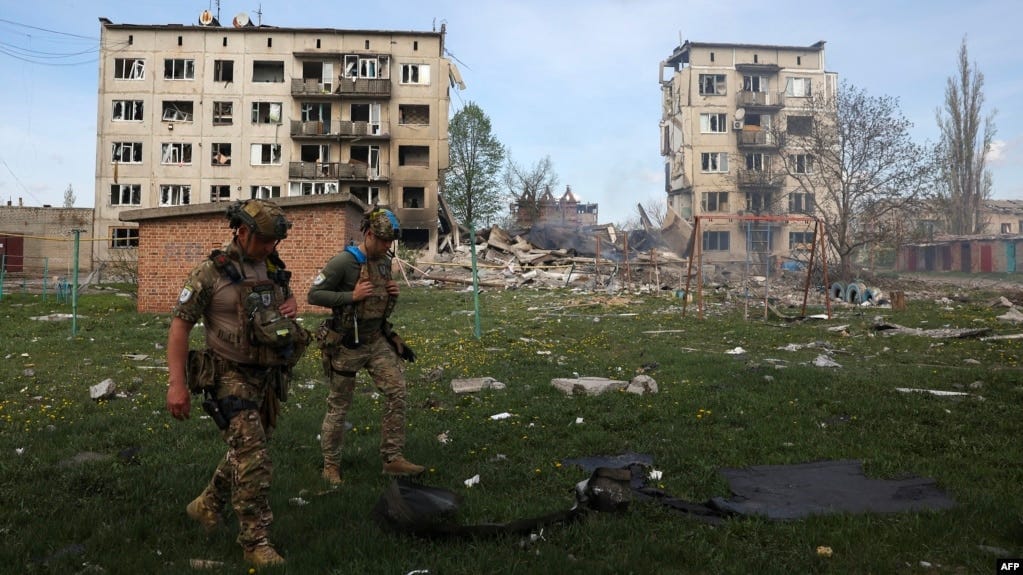 Officers of a special police force walk in front of apartment buildings destroyed by air bombs during the evacuation of local residents from the village of Ocheretine in the Donetsk region on April 15, 2024, amid the Russian invasion in Ukraine. Officers of a special police force walk in front of apartment buildings destroyed by air bombs during the evacuation of local residents from the village of Ocheretine in the Donetsk region on April 15, 2024, amid the Russian invasion in Ukraine.