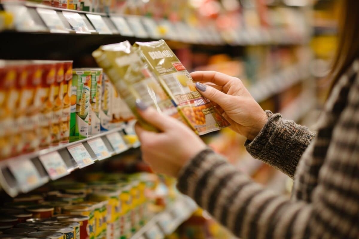 Woman holding packaged food item at the grocery store Woman holding packaged food item at the grocery store