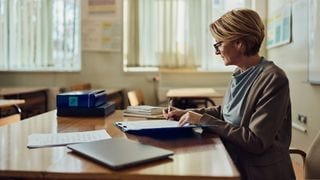 An older woman at a teacher's desk An older woman at a teacher's desk