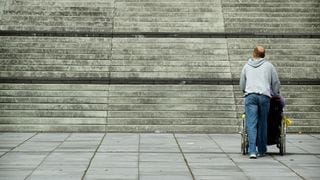 Man with a wheelchair at the bottom of a large staircase Man with a wheelchair at the bottom of a large staircase