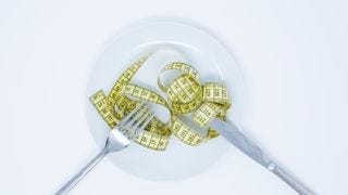A plate with a fork, knife, and measuring tape A plate with a fork, knife, and measuring tape