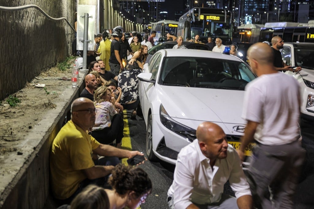 People take cover behind vehicles under a bridge along the side of a highway in Tel Aviv on October 1, 2024. People take cover behind vehicles under a bridge along the side of a highway in Tel Aviv on October 1, 2024.