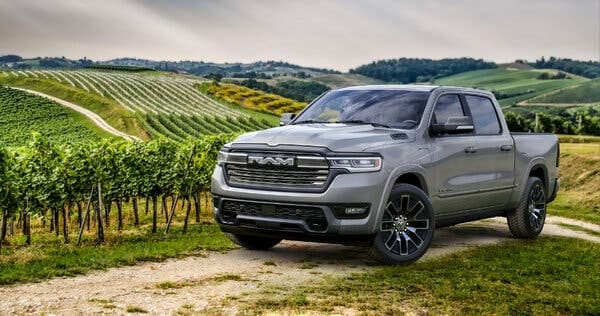 A large, gray Ram truck on a dirt path in front of rows and rows of grape vines. A large, gray Ram truck on a dirt path in front of rows and rows of grape vines.