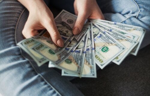 Person holding $100 bills Person holding $100 bills