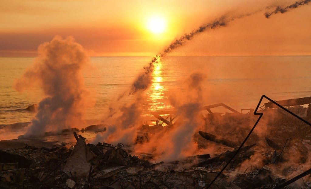 The smouldering wreck of houses, with the sun setting over the sea visible in the background. The smouldering wreck of houses, with the sun setting over the sea visible in the background.