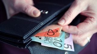 A hand pulling Australian cash out of a wallet A hand pulling Australian cash out of a wallet