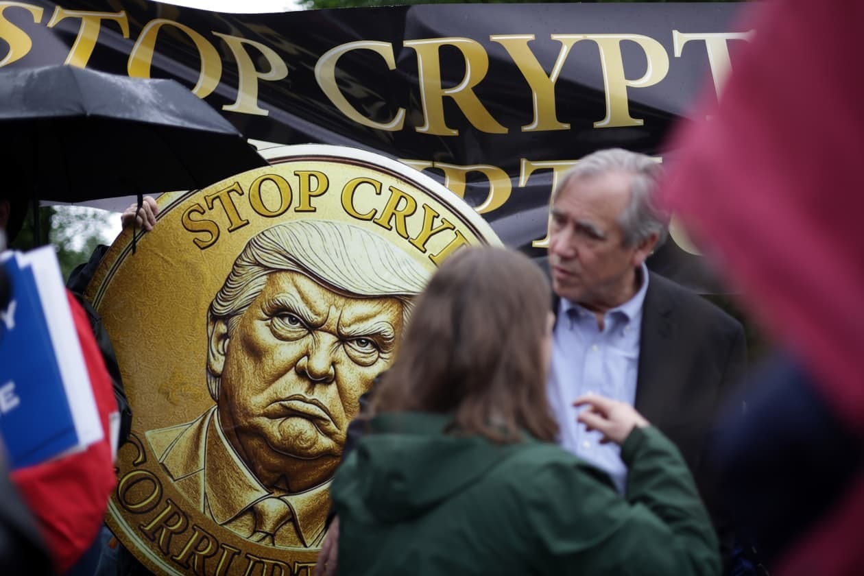 Protesters with signs, one depicting a stern Donald Trump, outside Trump National Golf Club. Protesters with signs, one depicting a stern Donald Trump, outside Trump National Golf Club.