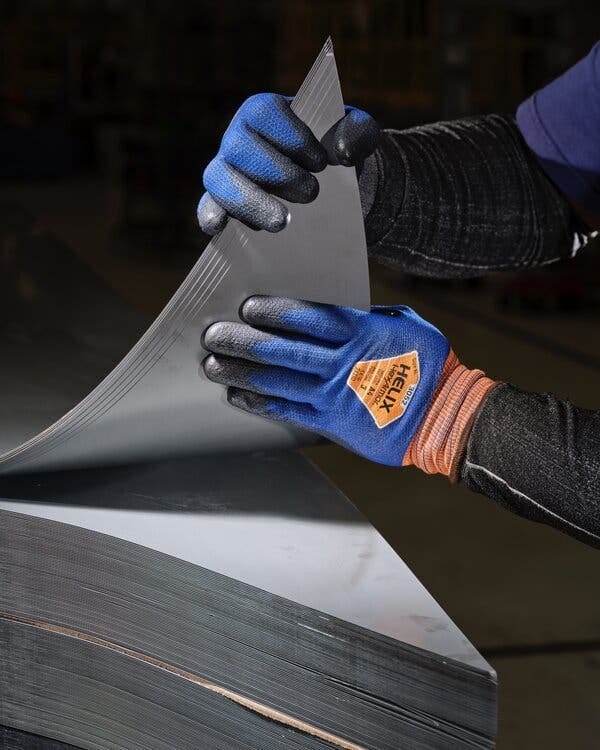Two gloved hands peeling back sheets of steel from a stack. Two gloved hands peeling back sheets of steel from a stack.