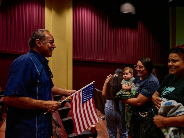 Alvaro Preciado, holding an American flag and smiling with several other people.