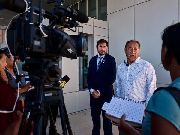 Alvaro Preciado, speaking to reporters. A camera faces him in the foreground.