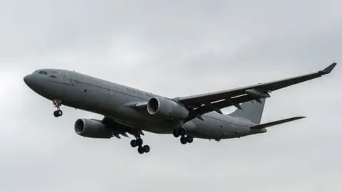 NurPhoto via Getty Images A grey RAF Voyager seen flying through cloudy skies